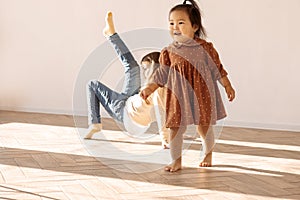 Little girls of different races in casual clothes play in living room of house on sunny day. Cute multiethnic children have fun