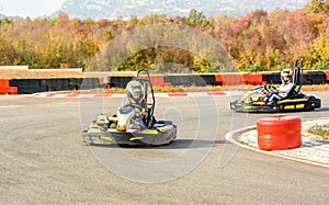 Little girls are driving Go- Kart car in a playground racing track