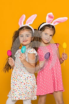 Little girls with Easter bunny ears holding colorful eggs
