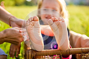 Little girls feet sitting in a wicker basket on a sunny day