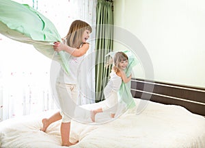 Little girls fighting with pillows in bedroom