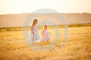 Little girls going on sloping wheat field sunset