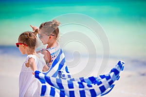 Little girls having fun running with towels on tropical beach