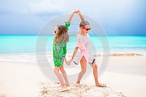 Little girls having fun at tropical beach playing together at shallow water. Adorable little sisters at beach during