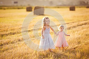 Little girls holding hands stand on sloping field