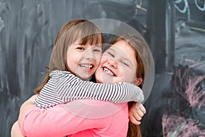Little girls hugging in front of chalkboard