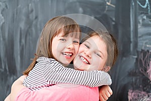 Little girls hugging in front of chalkboard