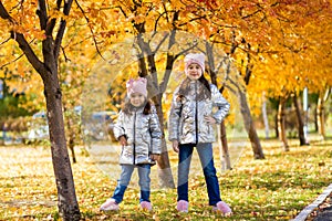 Little girls in identical clothes have fun walking in the autumn Park