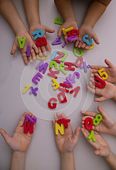 Little girls learning the alphabet using colored letters, top view