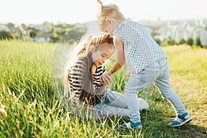 Little girls are looking at insects in the green grass on the field.