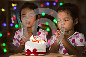 Little girls make folded hand to wish the good things for their birthday photo