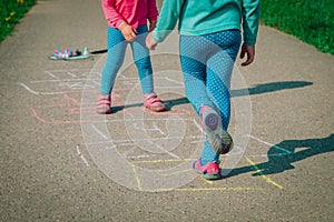 Little girls play hopscotch on playground, kids outdoors