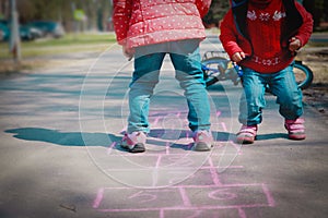 Little girls play hopscotch on playground, kids outdoors