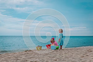 little girls play with sand on beach vacation