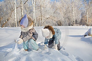 Little girls play with snow in a park in winter