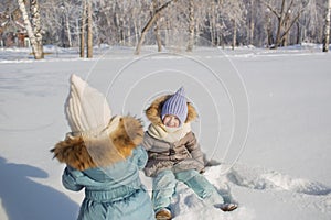 Little girls play in a snow in a winter park