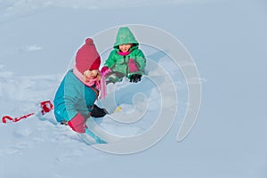 Little girls play in winter, kids dig snow, seasonal activities