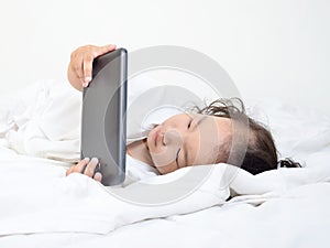 Little girls playing on a tablet computing device - laying on th