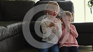 Little girls are praying to God in the living room crossed their arms and stand on kneel.