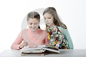 Little girls read books at the table on white