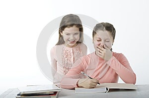 Little girls read books at the table on white