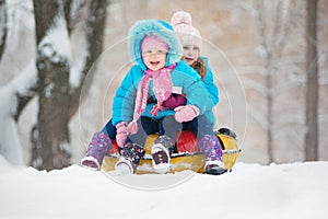 Little girls ride a snow tube. Winter holidays, holiday for children in winter. Winter city park