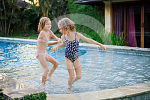 Little girls running in the swimming pool. Sisters playing together. Summer concept. Family activities. Happy childhood. Vacation