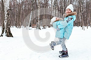 Little girls, sisters are walking, having fun in snowy winter park. Stylish clothes, blue jackets with fur,warm pants with