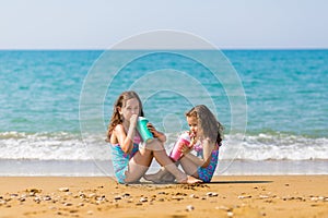 Little girls sit sit opposite each other and drink from colored beautiful cocktail glasses Family vacation concept