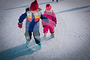 Little girls skating together in snow, kids winter activities