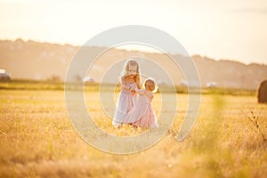 Little girls spin together on sloping wheat field