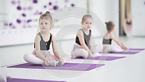 Little girls stretching and doing exercises in ballet school