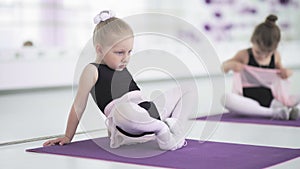 Little girls stretching and doing exercises in ballet school