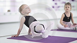 Little girls stretching and doing exercises in ballet school