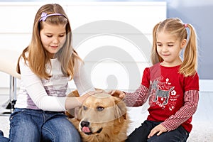 Little girls stroking dog smiling