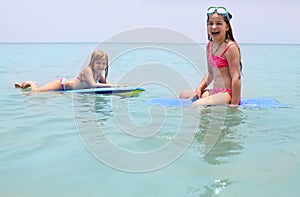 Little girls with surfing boards playing on tropical ocean beach. Summer water fun for surfer kids