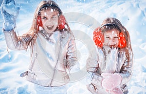 Little girls throw snowball in park. Theme Christmas holidays winter new year. Two adorable young sisters girls having