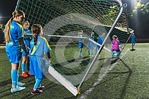 little girls trying to change the position of the football goal-net, full shot