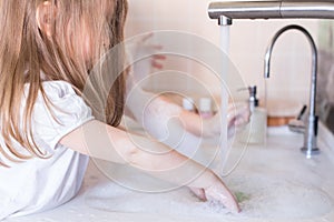 Little girls wash their hands in the sink with soap in the foam. Protection against coronovirus covid-2019 using personal hygiene