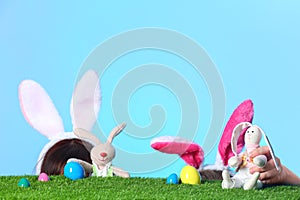 Little girls wearing rabbit ears headbands and playing with toy Easter bunnies on green grass surface