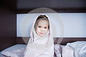 Little girls wrapped in blanket going to sleep sitting on bed. sleep schedule in domestic lifestyle. cute child portrait