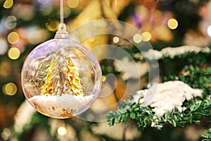 A little golden Christmas tree in the crystal clear bauble ball hangs as a decoration