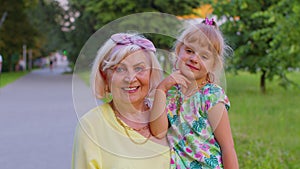 Little granddaughter child embracing kissing with her grandmother in park, happy family relationship