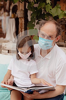Little granddaughter in a face mask hugs and wants to protect grandfather from an epidemic