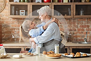 Little granddaughter hugging her happy grandmother during snack time