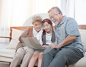 Little granddaughter teach senior elder to surf internet using computer and technology& modern lifestyle.Happy asian grandparent