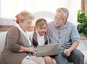 Little granddaughter teach senior elder to surf internet using computer and technology& modern lifestyle.Happy asian grandparent