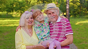 Little granddaughter together with senior grandmother and grandfather in park, family relationship