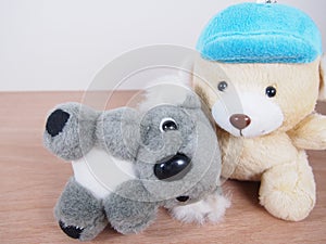 Little gray koala bear doll, lie down on light beige bear`s lap