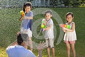 Little guys using water guns to spray their father